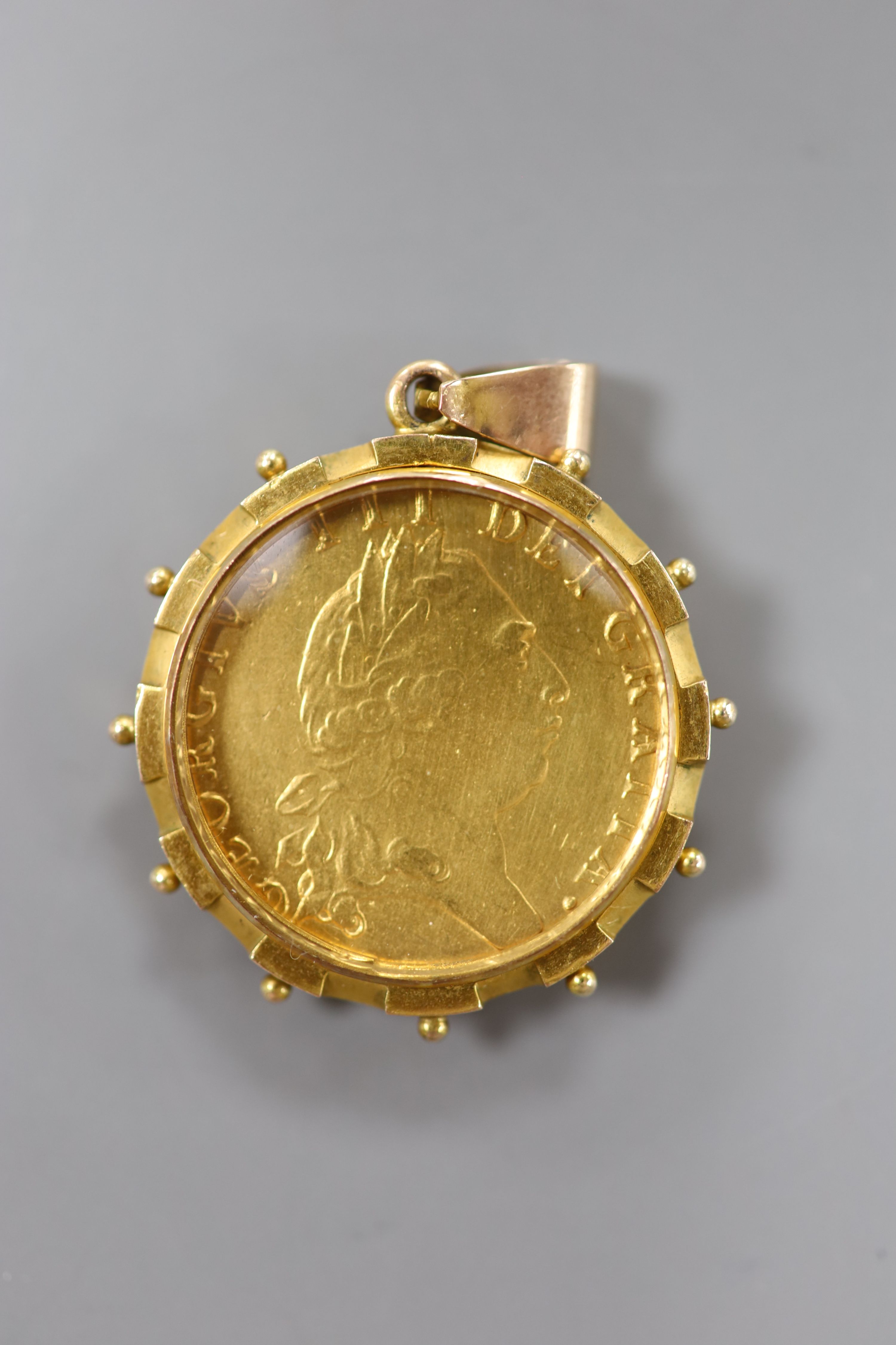 A George III spade guinea, 1794 in a glazed 9ct gold mount, gross 17.2 grams.